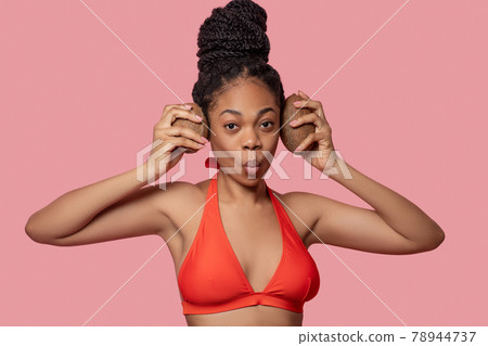 Dark-skinned woman holding coconuts and looking enjoyed 78944737