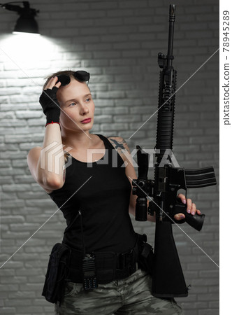 a young female soldier poses with an automatic rifle with a telescopic sight in a shooting range a young female soldier poses with an automatic rifle with a telescopic sight in a shooting range 78945289