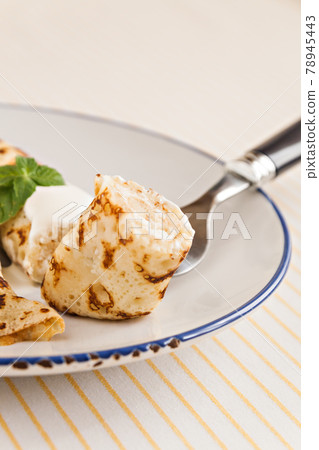 thin crepes rolled pancakes with sour cream mint on a plate 78945443