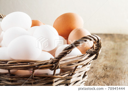 Chicken eggs in the basket on wooden background Chicken eggs in the basket on wooden background 78945444