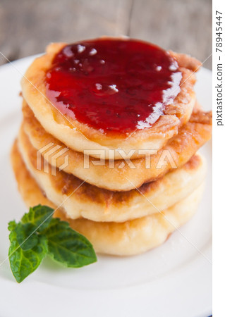 stack of cheesecakes with jam on a white plate on a dark wooden background stack of cheesecakes with jam on a white plate on a dark wooden background 78945447