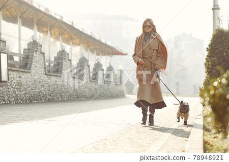 Elegant woman in a brown coat with black bulldog 78948921