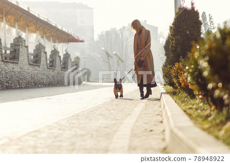Elegant woman in a brown coat with black bulldog 78948922
