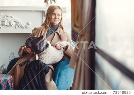 Elegant woman in a brown coat with black bulldog 78948923