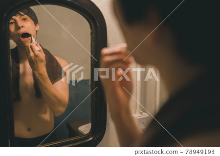 A young man brushing his teeth after taking a bath 78949193