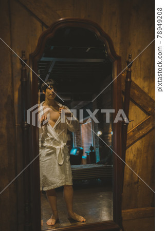 A man in a bathrobe looking in the mirror 78949208