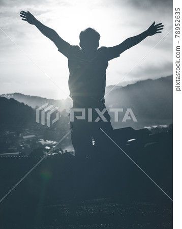 Hikers in silhouette stands on the rock in the beautiful mountains with rising hands at sunrise sky background 78952635