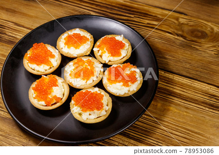 Tartlets with red caviar and soft cheese on a wooden table 78953086