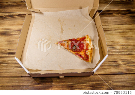 Last slice of pizza in cardboard box on a wooden table. Concept for home delivery of food, fast food, delivery of pizza Last slice of pizza in cardboard box on a wooden table. Concept for home delivery of food, fast food, delivery of pizza 78953115