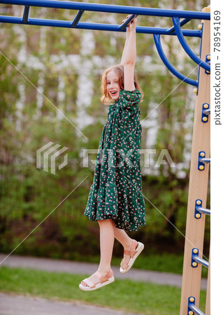 Smiling child hanging on monkey bars outdoors Smiling child hanging on monkey bars outdoors 78954169