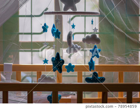 Cot mobile over the babies small bed has purple net over and the baby crib is near the window close up side view, Cot mobile over the babies small bed has purple net over and the baby crib is near the window close up side view, 78954859