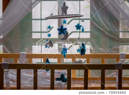 Cot mobile over the babies small bed has purple net over and the baby crib is near the window close up side view, Cot mobile over the babies small bed has purple net over and the baby crib is near the window close up side view, 78954860