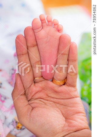 New born baby girls feet fit inside mothers fingers, three weeks old infant, pink small fingers, close up photograph. Mothers infinity love concept. New born baby girls feet fit inside mothers fingers, three weeks old infant, pink small fingers, close up photograph. Mothers infinity love concept. 78954862