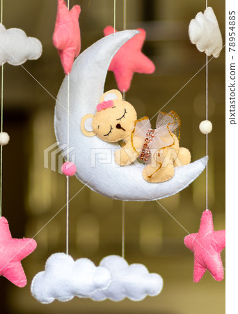 Dreamy baby crib mobile close up, hangs over the baby bed, cute bear sleeping on the moon, stuffed fluffy felt handmade cot toy for newborn babies. Dreamy baby crib mobile close up, hangs over the baby bed, cute bear sleeping on the moon, stuffed fluffy felt handmade cot toy for newborn babies. 78954885