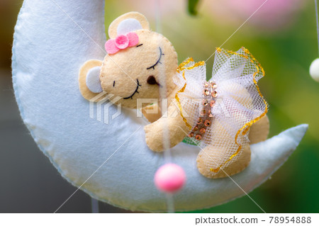 Dreamy baby crib mobile close up, hangs over the baby bed, cute bear sleeping on the moon, stuffed fluffy felt handmade cot toy for newborn babies. Dreamy baby crib mobile close up, hangs over the baby bed, cute bear sleeping on the moon, stuffed fluffy felt handmade cot toy for newborn babies. 78954888