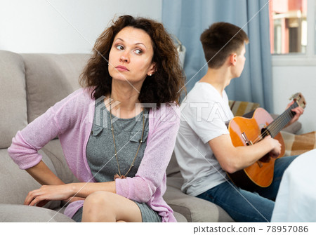 Woman upset because of son playing guitar 78957086