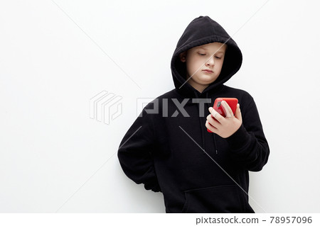 little boy in a black hood with a smartphone 78957096