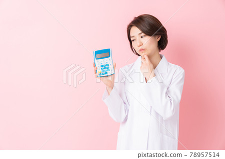 A woman in a white coat thinks about a calculator 78957514