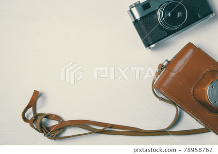 Vintage camera with leather case on a wooden white background. Vintage camera with leather case on a wooden white background. 78958762