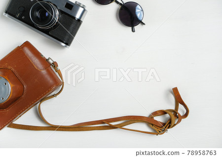 Vintage camera with leather case and sunglasses on a wooden white background. Vintage camera with leather case and sunglasses on a wooden white background. 78958763