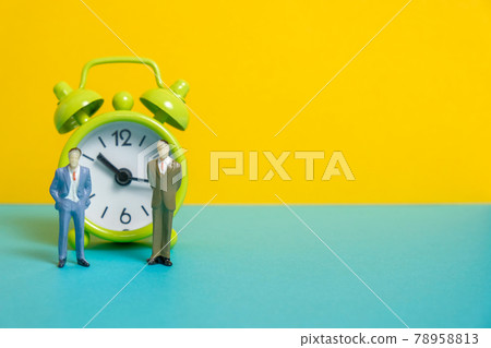 Men dummy next to a green vintage clock on a yellow background. Men dummy next to a green vintage clock on a yellow background. 78958813
