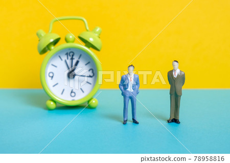 Men dummy next to a green vintage clock on a yellow background. Men dummy next to a green vintage clock on a yellow background. 78958816