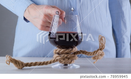 female hand shows the sign CANNOT, STOP on a wine glass, tied with a jute rope. The concept of female hand shows the sign CANNOT, STOP on a wine glass, tied with a jute rope. The concept of 78959945
