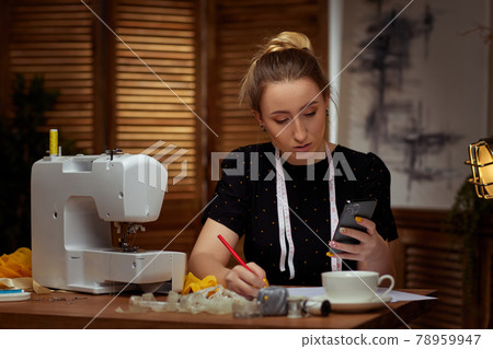 Beautiful young seamstress working on sewing machine Beautiful young seamstress working on sewing machine 78959947