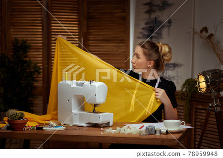 Beautiful young seamstress working on sewing machine Beautiful young seamstress working on sewing machine 78959948