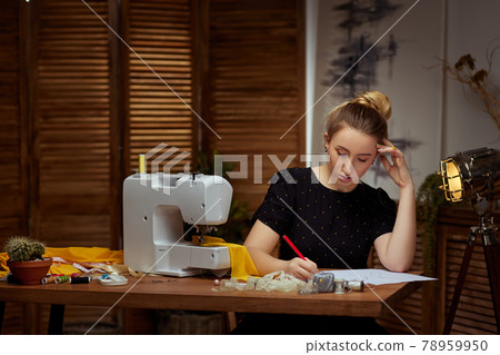 Beautiful young seamstress working on sewing machine Beautiful young seamstress working on sewing machine 78959950