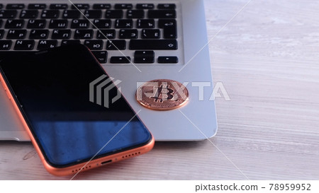 Golden bitcoin on the desk with laptop and smartphone. Crypto is Digital Money within the blockchain Golden bitcoin on the desk with laptop and smartphone. Crypto is Digital Money within the blockchain 78959952