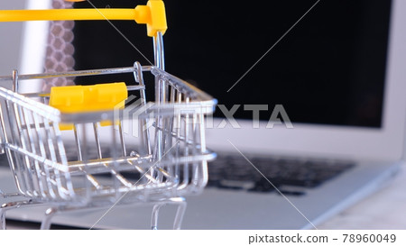 shopping basket next to a laptop on background. Copy space. Online shopping concept. shopping basket next to a laptop on background. Copy space. Online shopping concept. 78960049