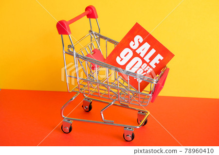 Trolley on a red-yellow background with the announcement of a 90% discount. The concept of sales. 78960410
