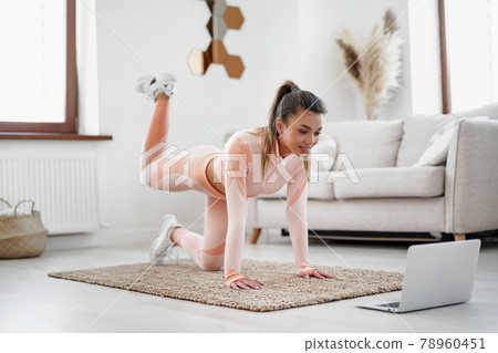 Young woman in sportswear using laptop to watch workout video tutorials at home 78960451