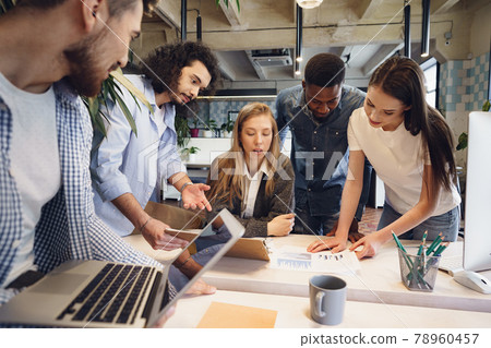 Team of diverse coworkers in modern office discuss their project together Team of diverse coworkers in modern office discuss their project together 78960457