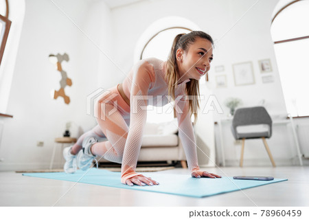 Sporty young woman doing plank exercise indoors at home Sporty young woman doing plank exercise indoors at home 78960459