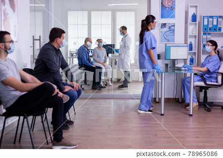 Medical assistants talking in hospital reception wearing protection masks Medical assistants talking in hospital reception wearing protection masks 78965086