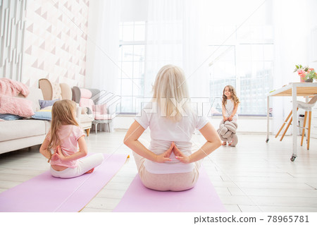 Smiling blond mother on yoga mat with cute playful daughter do exercises. 78965781