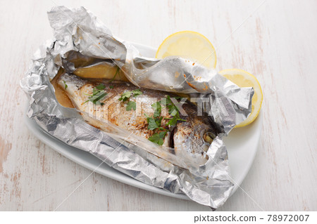 baked fish with lemon in aluminium foil on ceramic background baked fish with lemon in aluminium foil on ceramic background 78972007