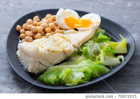 boiled cod fish with cabbage, chick pea and egg on dark dish 78972015