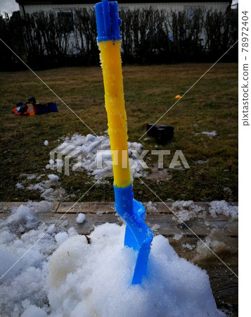 last snow with a kids spade on veranda 78972404