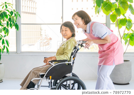 Nursing staff and senior women pushing a wheelchair 78972770