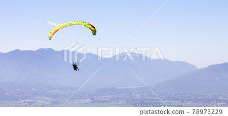 Adventurous Woman Flying on a paraglider around the Canadian Mountain Landscape Adventurous Woman Flying on a paraglider around the Canadian Mountain Landscape 78973229
