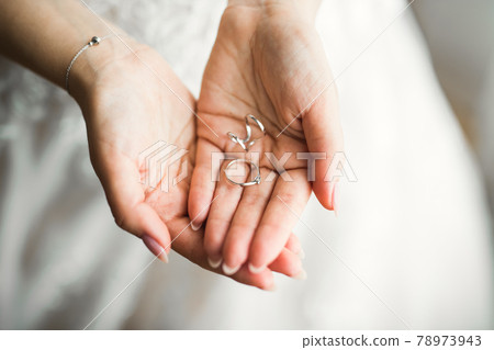 Beautiful luxury bride in elegant white dress holds wedding rings in the hands Beautiful luxury bride in elegant white dress holds wedding rings in the hands 78973943