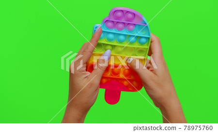 Hands playing colorful squishy silicone bubbles sensory toy game isolated on chroma key background 78975760