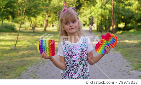 Children girl kid holding squeezing anti-stress touch screen push pop it popular toy in public park Children girl kid holding squeezing anti-stress touch screen push pop it popular toy in public park 78975818