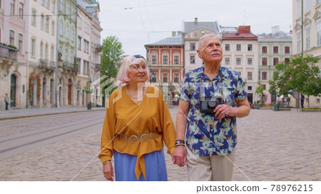 Senior old stylish tourists man, woman, grandmother, grandfather family having a walk in summer city 78976215