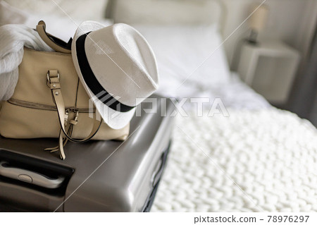 Gray suitcase with handbag and summer hat packing ready to travel vacation on bed at home or hotel Gray suitcase with handbag and summer hat packing ready to travel vacation on bed at home or hotel 78976297