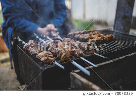 A man prepares on the grill delicious barbecue. shish kebabs on skewers A man prepares on the grill delicious barbecue. shish kebabs on skewers 78978389