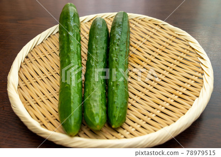 Round bamboo colander and green cucumber Round bamboo colander and green cucumber 78979515